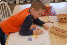 Child coloring on paper at a table.