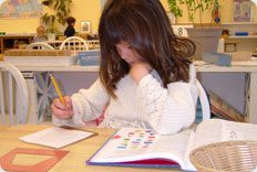 Child writing in a classroom setting.