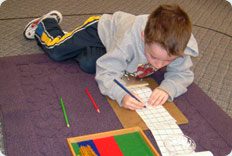 Child drawing on paper with colored pencils.
