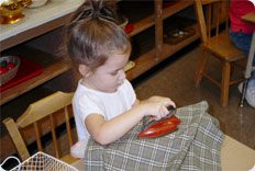 Child playing with toy iron and fabric.