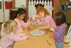 Children crafting with beads at a table.